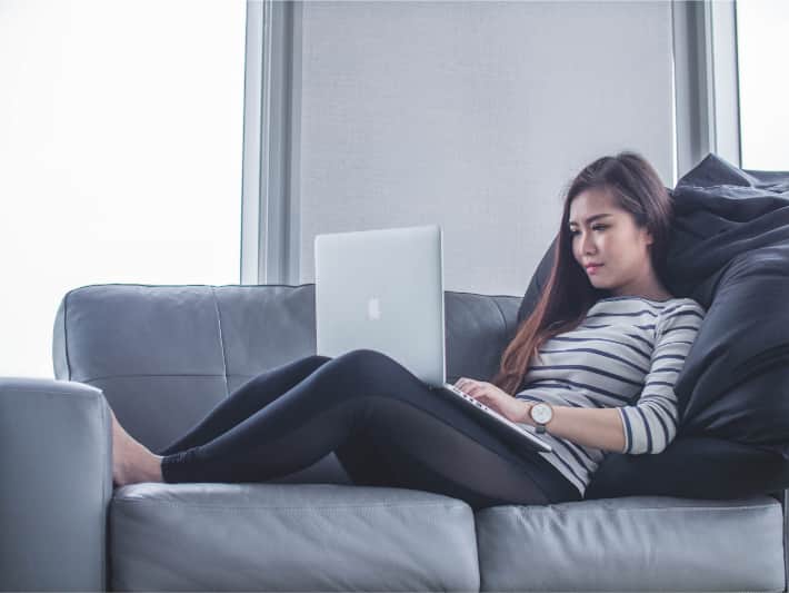 Kvinna som använder en bärbar dator i soffan