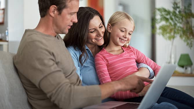 En privat blogg kan hindra främlingar från att få reda på personlig information om din familj. En bild visar två föräldrar och deras dotter som sitter i en soffa och tittar på en surfplatta tillsammans.